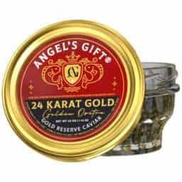 A glass jar of caviar with a gold lid labeled "Angel's Gift 24 Karat Gold Golden Osetra Gold Reserve Caviar, Net Wt 50g (1.75 oz)." The lid features a red and gold design with two stylized fish and a crest in the center. Caviar eggs are visible through the clear glass jar.