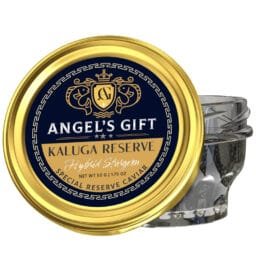 A glass jar of caviar with a gold lid labeled "Angel's Gift Kaluga Reserve Hybrid Sturgeon Special Reserve Caviar, Net Wt 50g (1.75 oz)." The lid features a blue and gold design with two stylized fish and a crest in the center.